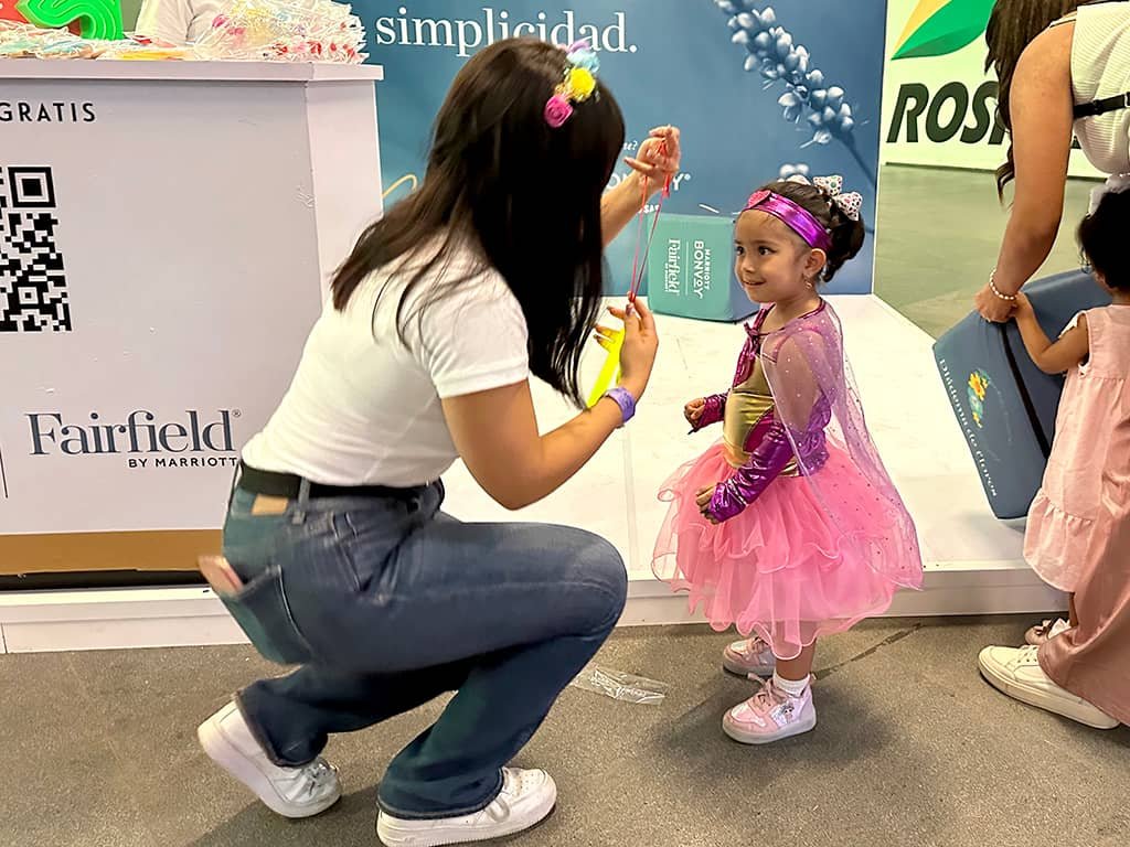 Edecan entregando artículos promocionales personalizados en una expo